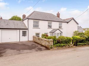 a white house with a garage and a driveway at 3 Bed in Bude 26425 in Morwenstow