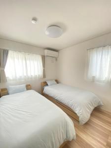 藤沢市にある湘南片瀬HOMEのベッド2台(白いシーツ、窓付)