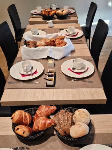 una mesa larga con cruasanes y repostería en los platos en Les chambres de la Vaulx-Renard, en La Gleize