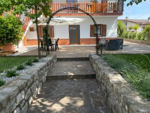 a garden with a stone retaining wall and a patio at All'ombra del tiglio Bed&Breakfast in Doberdò del Lago