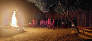 a group of people standing around a fire at night at MONKEY MOUNTAIN LODGE in Mtende