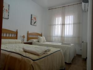 a white room with two beds and a window at Alojamiento Vacacional Inma in Cazorla