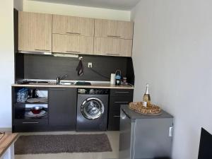 een keuken met een wasmachine en een wastafel bij Лятно студио in Sveti Vlas