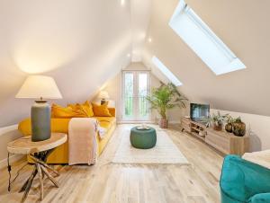 a living room with a yellow couch and a skylight at Roseland Penthouse - Arundel in Arundel