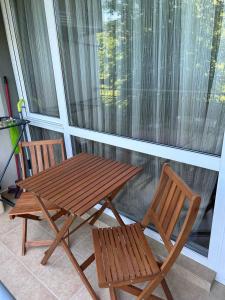 een houten tafel en twee stoelen naast een raam bij Лятно студио in Sveti Vlas