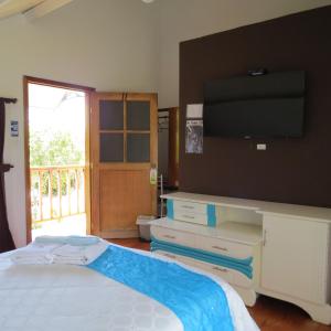 a bedroom with a bed with a tv on the wall at Hosteria Airport Garden in Tababela