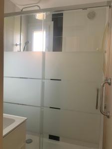 y baño con ducha de cristal y lavabo. en Appartement jardin Cap d'Agde en Cap d'Agde