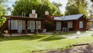a house with a sprinkler in the yard at Cabañas "El Valle" in San Rafael