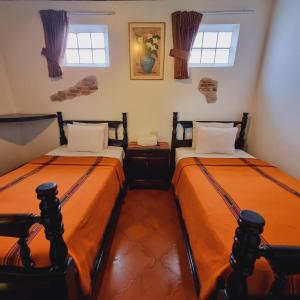 two beds in a room with two windows at La Quinta Santa Lucia in Antigua Guatemala