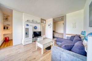 ein Wohnzimmer mit einem blauen Sofa und einem Tisch in der Unterkunft Ferienpark - Haus F, App 0FEG01 in Heiligenhafen