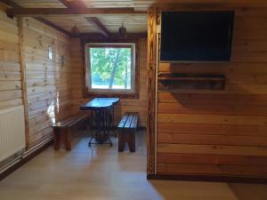 a room with a tv and a table in a cabin at Zielony Domek Papiernia in Lipusz