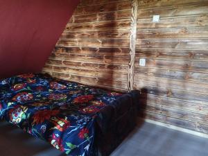 a bed in a room with a wooden wall at Zielony Domek Papiernia in Lipusz