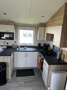uma pequena cozinha com armários brancos e um lavatório em MOONSTONE Lymington em Leysdown-on-Sea