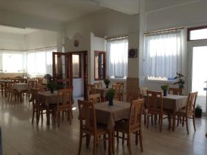 a dining room with tables and chairs and windows at Hotel Meltemi in Adamantas