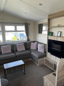 a living room with a couch and a flat screen tv at MOONSTONE Lymington in Leysdown-on-Sea