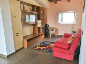 uma sala de estar com um sofá vermelho e uma mesa em 2 bedrooms apartement with furnished balcony and wifi at Casalvecchio Siculo 6 km away from the beach em Casalvecchio Siculo