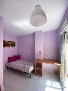 a bedroom with purple walls and a bed and a desk at Paraiso MEDITERRANEO in Puerto Marino
