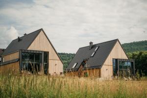 two barns with windows in a field of tall grass at Apartamenty Na Potokach in Żegocina