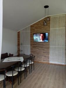 una sala da pranzo con tavolo e TV a parete di U Anastasii i Sofii bilya richki a Mykulychyn