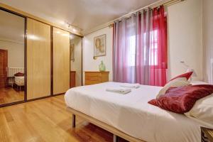 1 dormitorio con 1 cama blanca grande y cortinas rojas en Casa Iruña by Clabao, en Pamplona