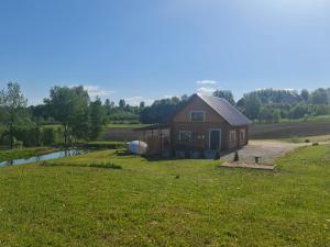 uma casa numa colina com um campo e um rio em Holiday home Tūjas em Kraslava