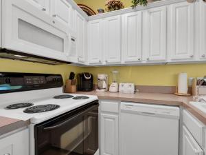 a kitchen with white cabinets and a stove top oven at Caribbean Breeze by Newman-Dailey in Destin +26 photos