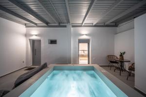 a large swimming pool in a room with a table at White Note Luxury Suites in Perivolos