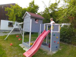 dos niños jugando en un tobogán en una casa de juegos en Widernhof, en Prien am Chiemsee