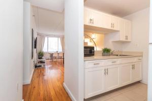 a kitchen with white cabinets and a hard wood floor at Central Park North - Quiet Place in New York