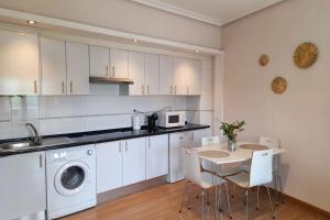 トレドにあるApartamento Castilla 30 Bis - Parking Publico Gratuitoの白いキャビネットとテーブルと椅子のあるキッチン
