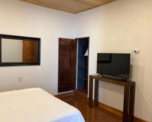 um quarto com uma cama e uma televisão de ecrã plano em Casa Stella Centro Histórico em Guatemala