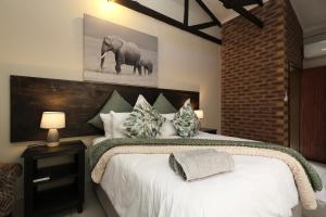 a bedroom with a large bed with an elephant picture on the wall at Hhusha Hhusha in Malelane