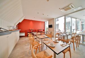 un restaurante con mesas y sillas y una pared roja en Aparthotel Adagio Strasbourg Place Kleber, en Estrasburgo