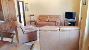 uma sala de estar com mobiliário de couro e uma televisão em One bedroom apartement with furnished balcony and wifi at Montagnareale 5 km away from the beach em Montagnareale
