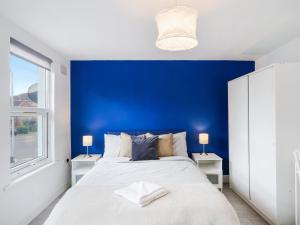 a bedroom with a blue accent wall and a bed at Large Home for Contractors & Families - Garden & Amenities in London