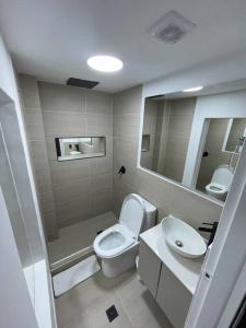 a bathroom with a toilet and a sink and a mirror at Laureles best location with Jacuzzi and AC in Medellín