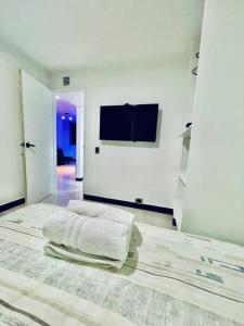 a white room with a bed with towels on it at Laureles best location with Jacuzzi and AC in Medellín
