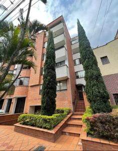 a building with two tall trees in front of it at Laureles best location with Jacuzzi and AC in Medellín
