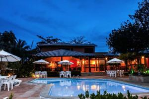 um resort com uma piscina com cadeiras e guarda-sóis em Pousada Bichelenga em Imbassaí