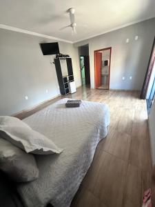 um quarto com uma cama com um edredão branco em Pousada Serra Mística em São Thomé das Letras