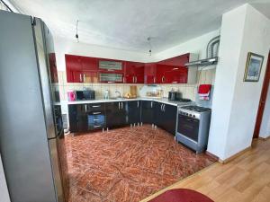 una cocina con armarios rojos y electrodomésticos negros en Casa de vacanta, en Borsec