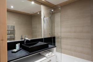 La salle de bains est pourvue d'un lavabo et d'une douche en verre. dans l'établissement Le Roc Des Tours, au Grand-Bornand