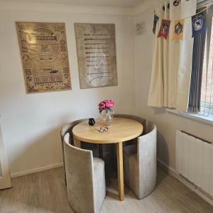 a table and chairs with a vase of flowers on it at Godricks Hollow House in Watford