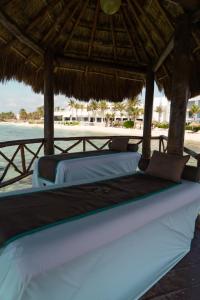 two beds under a straw umbrella on the beach at The Sens Tulum Riviera by Oasis in Akumal