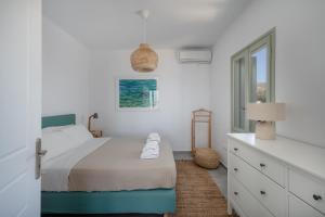 a white bedroom with a bed and a window at Sea Houses SERIFOS in Rámos