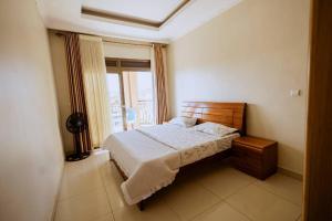 ADRIEL HOMES WOODLAND CENTEr في كيغالي: غرفة نوم بسرير ونافذة كبيرة
