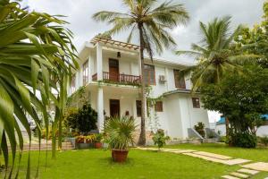 une maison blanche avec des palmiers dans la cour dans l'établissement Getaway Experience Villa., à Dar es Salaam