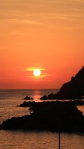 un coucher de soleil sur l'océan avec des rochers dans l'eau dans l'établissement Cuccaro Club - Val di Vara e Cinque Terre, à Rocchetta di Vara