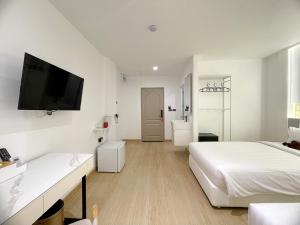 a white bedroom with two beds and a flat screen tv at Arawana Express Sukhumvit 22 in Bangkok