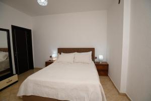 a bedroom with a bed with white sheets and a tv at Shuli's Apartments in Pogradec